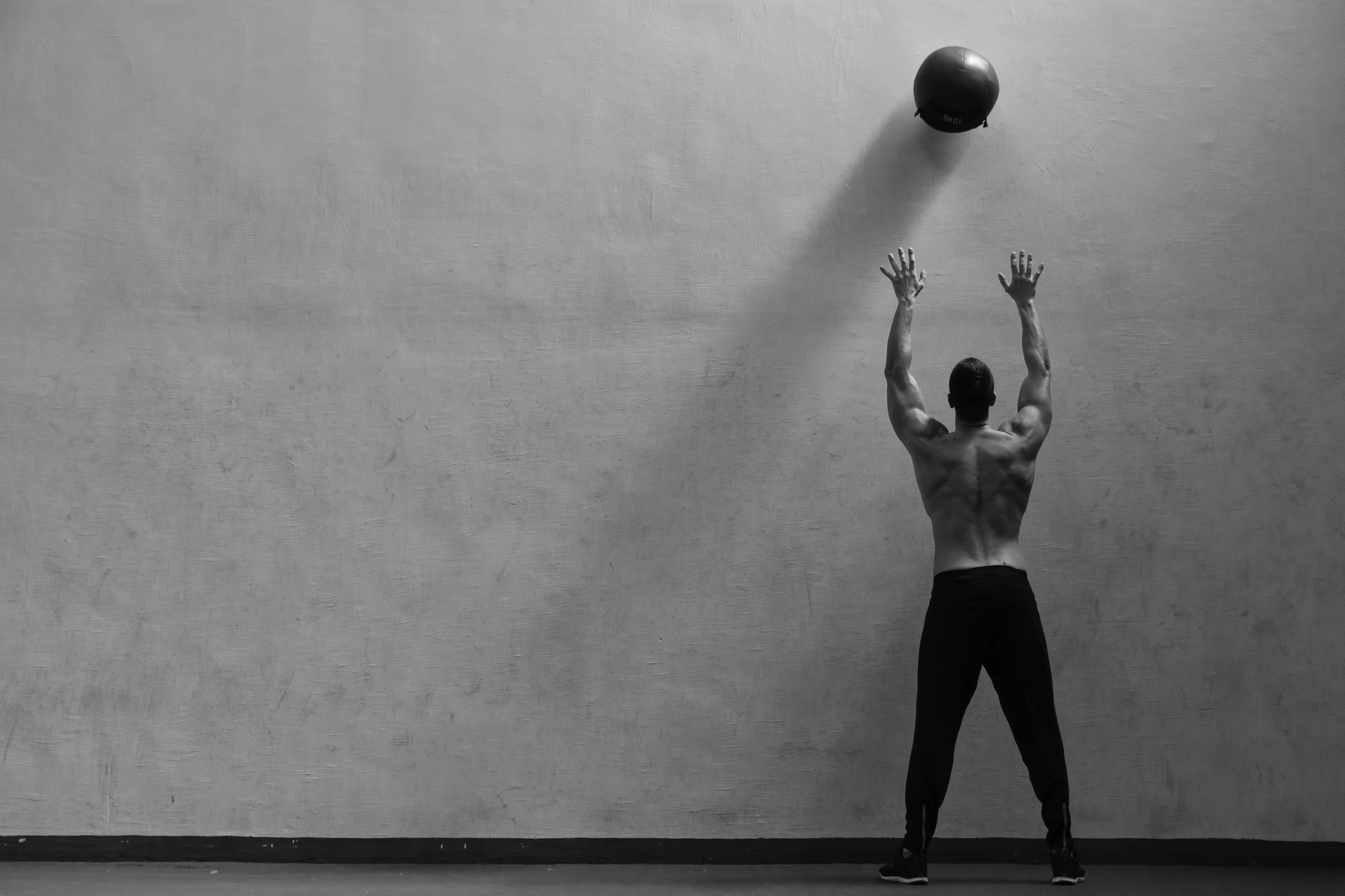 Bodybuilder doing wall ball exercise